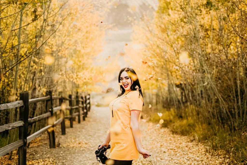 Shayla Marin with camera in fall leaves in victor colorado